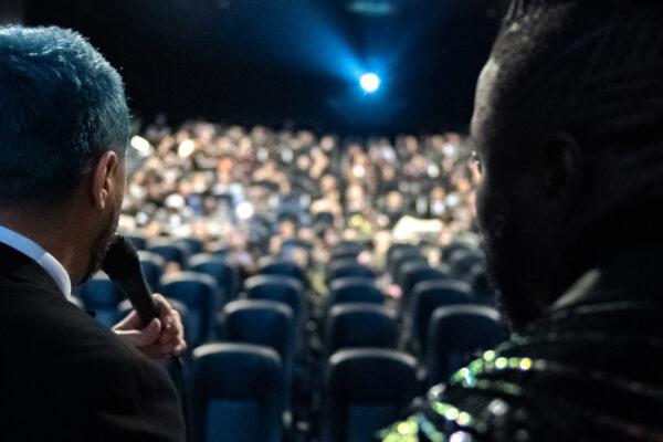 Director Yuri Alves and Grind star Robert Willmote presenting in front of crowd in SHAQ-DX theater